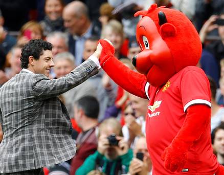 The famous manchester united fan and golf supremo high fives the Red Devil mascot. 